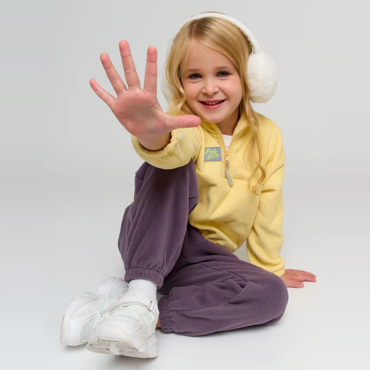 Ребёнок в флисовом костюме бегает на детской площадке